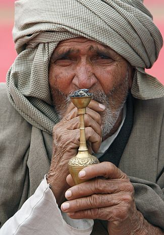A member of the Jat community smokes hookah during a rally in New Delhi