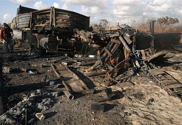A man looks at destroyed weapons belonging to forces loyal to Libyan leader Muammar Gaddafi, after a coalition air strike, along a road between Benghazi and Ajdabiya