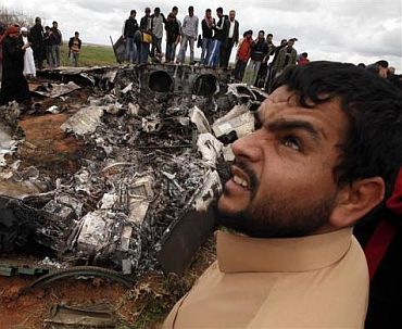 People look at a US Air Force F-15E fighter jet after it crashed near the eastern city of Benghazi