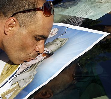 A supporter of Libya's leader Muammar Gaddafi kisses a picture of Gaddafi during a protest in front of the United Nations office in Tripoli