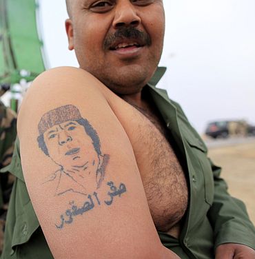A Libyan government soldier displays a tattoo of Libyan leader Muammar Gaddafi at the west gate of town Ajdabiyah