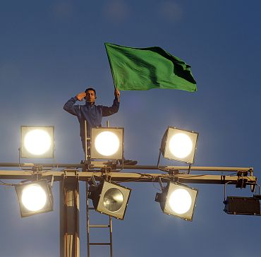 A supporter of Libya's leader Muammar Gaddafi holds a Libyan flag atop floodlights at Green Square in Tripoli