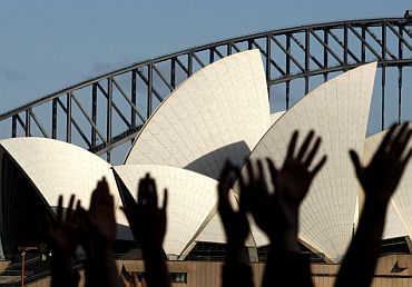 Yoga enthusiasts perform sun salutations in front of Sydney's Opera House and Harbour Bridge in Australia