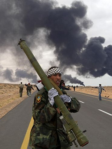A rebel holds a rocket propelled grenade launcher during clashes with pro-Gaddafi forces between Ras Lanuf and Bin Jawad