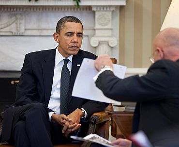 President Barack Obama studies a document held by Director of National Intelligence James Clapper during the Presidential daily briefing