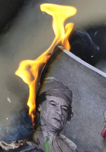 A man burns a picture of Libyan leader Muammar Gaddafi during a demonstration