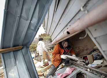 A woman retrieves belongings from her home destroyed in a tsunami at the port of the island of Oshima