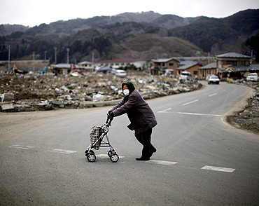 A woman crosses a street at an area destroyed by the earthquake and tsunami in Yamada town, Iwate Prefecture