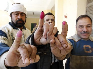 Egyptian men display their ink stained fingertips after casting their votes for a referendum on constitutional amendments at a polling station in Cairo