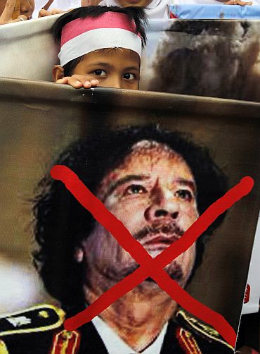 A child carries an poster denouncing Libyan leader Muammar Gaddafi