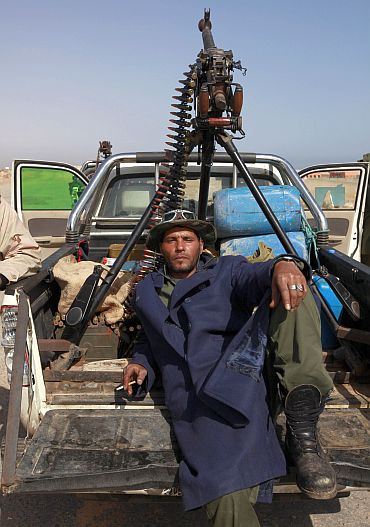 A rebel fighter rests on the road between Ras Lanuf and Bin Jawad in Libya