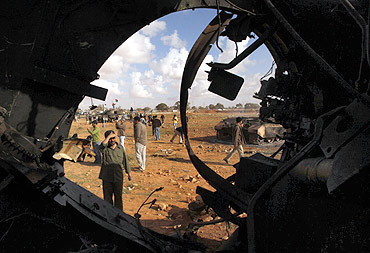 A man looks at a destroyed tank belonging to Gaddafi's forces after an air strike by coalition forces
