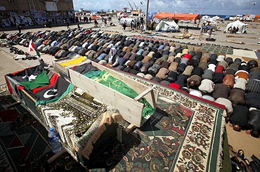 Mourners pray next to coffins containing bodies of Libyans killed by Gaddafi's forces during a funeral in Benghazi
