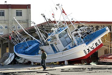 A man walks past a boat that was swept ashore after the March 11 earthquake and tsunami, at Otsu port in Kitaibaraki, Ibaraki prefecture