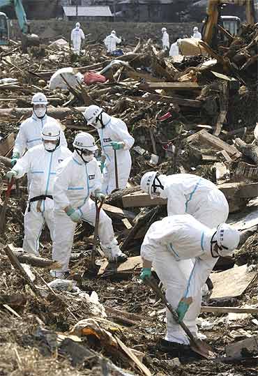 Police officers wearing protective suits search for victims of the earthquake and a tsunami in Fukushima prefecture in Minamisoma City, about 30km north of the crippled Fukushima Daiichi Nuclear Power Station