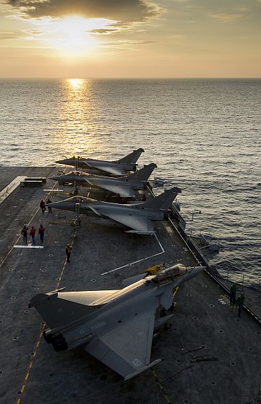 A French naval crew prepares Rafale fighter jets aboard the Charles de Gaulle aircraft carrier