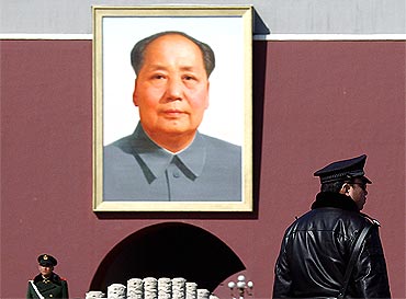 A policeman and paramilitary man stand guard in front of a giant portrait of the late Chairman Mao Zedong at Tiananmen Square in Beijing, China