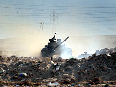 A  Libyan rebel tank advances  advances across the battlefield towards government troops