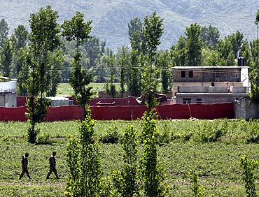 Pakistani soldiers walk past a compound, surrounded in red fabric, where locals reported a firefight took place overnight in Abbotabad
