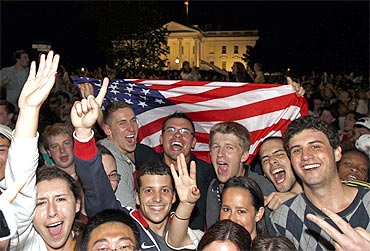 People cheer and wave US flags outside the White House