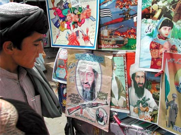 A boy looks at posters of Osama bin Laden displayed for sale at a roadside stall