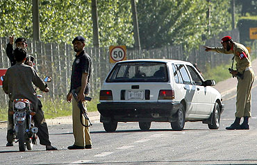 Policemen and a soldier halt traffic at a road block at Abbotabad
