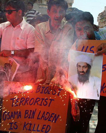 People hold placards and photographs of Al Qaeda leader Osama bin Laden as they celebrate his killing