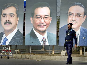 policeman walks past giant portraits of Pakistan's Prime Minister Yusuf Raza Gilani, China's Premier Wen Jiabao and Pakistan's President Zardari displayed along a road in Islamabad