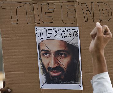 A demonstrator gestures in front of a portrait of Osama bin Laden during an anti-terrorism rally