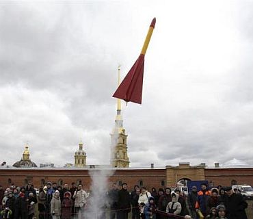 Spectators look at a self-made rocket model ascending during a show in front of the Peter and Pawel Fortress in St Petersburg, Moscow