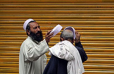 A resident tries on prayers hats for sale in Abbottabad
