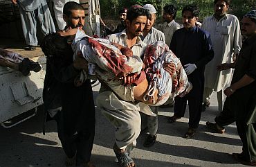 A hospital worker carries a man who was injured in a bomb attack at a paramilitary force academy in Charsadda