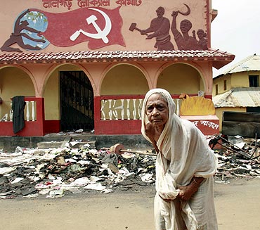 A woman walks past a damaged party office of the CPI-M at Lalgarh