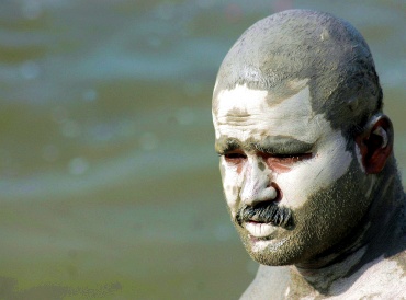 A man cools himself with mud on his body on the banks of the Ganga in Allahabad