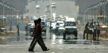 People walk through a mirage on a hot day at Rajpath in New Delhi