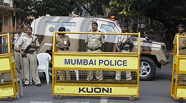 Police officers block a road with an armoured personnel carrier in Mumbai