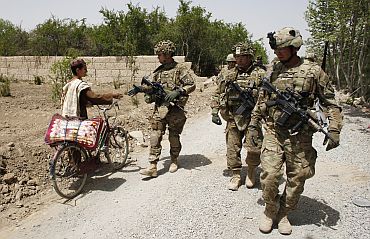 U.S. Army soldiers shake hands with a local youth as they walk near Combat Outpost Nolen in the Arghandab Valley, Kandahar