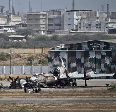 Officials stand near a damaged aircraft at the PNS Mehran base