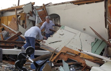 A man helps his wife Evelyn as they climb through the wreckage of what was once their children's home in Joplin