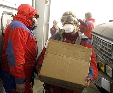-Emergency workers carry supplies at the Geirland farm near Kirkjubaejarklaustur