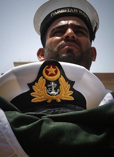 A member of the Pakistan Navy holds a national flag and a hat of navy officer Lieutent Yasir Abbas, who was killed during a gun battle against militants at the Mehran naval aviation base in Karachi a day earlier, after his burial in Lahore on May 24