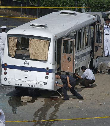 Security officials examine a bus after it was damaged by a bomb in Karachi April 28