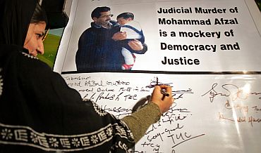 Tabassum Guru, wife of Afzal Guru, signs on a banner with her husband's and son's picture in Srinagar in 2006