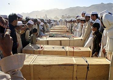 Residents stand over the caskets of those killed by a secondary blast at the site of a NATO tanker which was attacked in Pakistan's northwest Khyber Agency