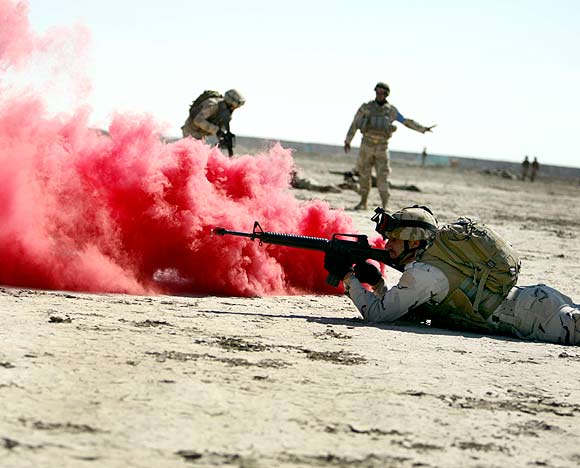 Coloured smoke is seen as an Iraqi soldier fires at targets during a training course supervised by the US Army at a military base in Nassiriya
