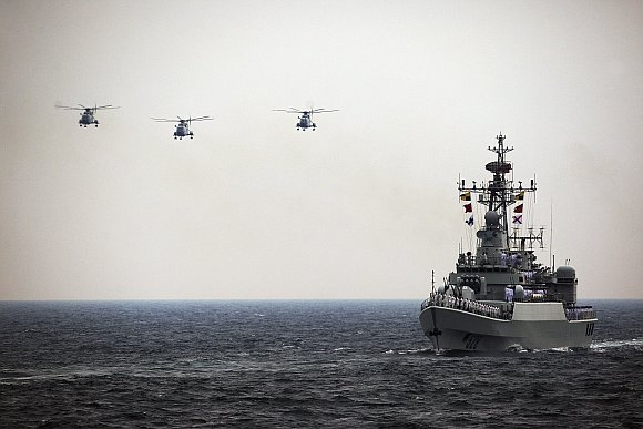 Helicopters accompany the Chinese Jiangwei II naval frigate Mianyang during an international fleet review to celebrate the 60th anniversary of the founding of the People's Liberation Army Navy in Qingdao, Shandong