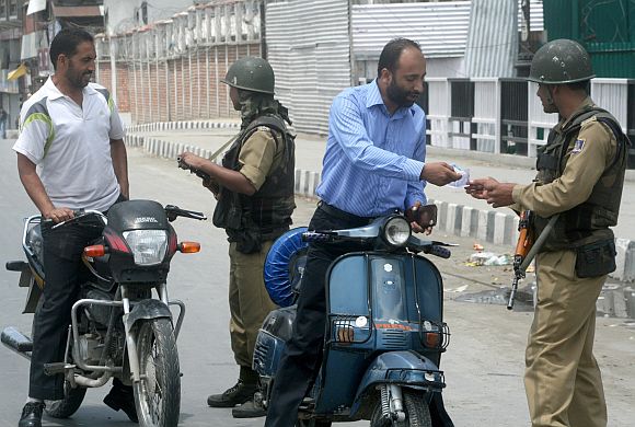 Paramilitary personnel frisking scooterists in Srinagar