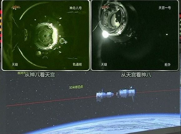 A view of China's Tiangong (Heavenly Palace) 1 module (top L) just before it docks with the Shenzhou 8 spacecraft (top R) is seen on a monitoring screen showing a computer animation (bottom) of the docking process at the Beijing Aerospace Flight Control Centre November 3