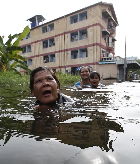 Residents walk through a flooded street in Bangkok on Sunday