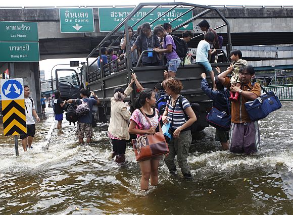 Residents disembark from a military truck as they are evacuated from a flooded area in Bangkok